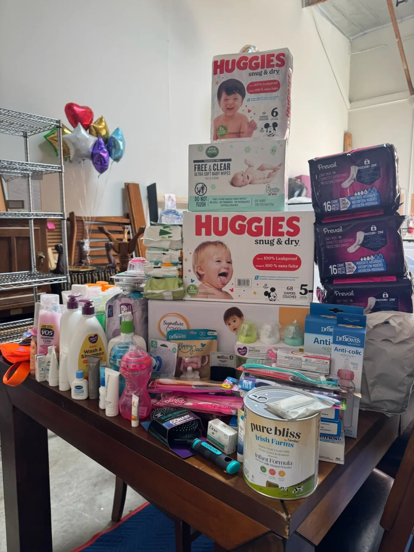A table piled with diapers, wipes, bottles, and hygiene supplies